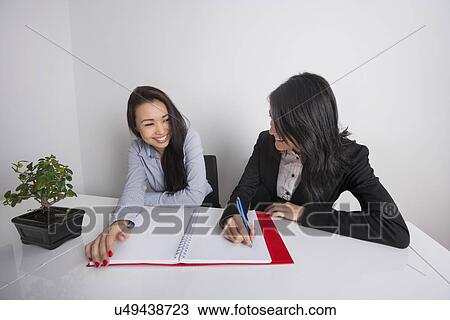 Happy businesswomen working at desk in office View Large Photo Image Stock Image - Happy businesswomen working at desk in office. Fotosearch