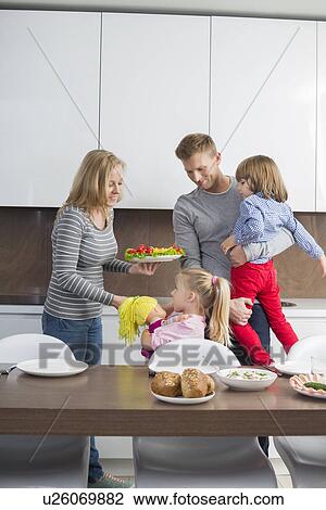 Happy family with children having meal in domestic kitchen View Large Photo Image Stock Image - Happy family with children having meal in domestic kitchen. Fotosearch