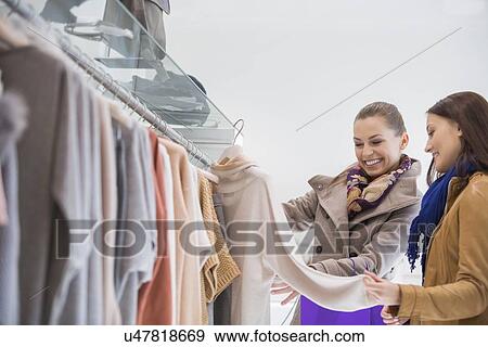 Happy friends choosing sweater in store View Large Photo Image Stock Photo - Happy friends choosing sweater in store. Fotosearch