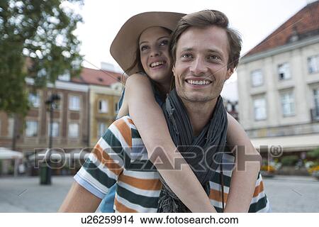 Happy man piggybacking woman on street during vacation View Large Photo Image Picture - Happy man piggybacking woman on street during vacation. Fotosearch