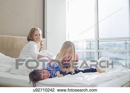 Happy parents looking at playful children in bedroom View Large Photo Image Stock Image - Happy parents looking at playful children in bedroom. Fotosearch