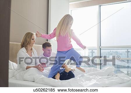 Happy parents looking at playful children in bedroom View Large Photo Image Stock Photography - Happy parents looking at playful children in bedroom. Fotosearch