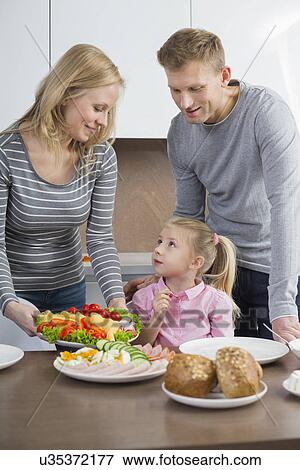 Happy parents with daughter having meal in kitchen View Large Photo Image Stock Photo - Happy parents with daughter having meal in kitchen. Fotosearch