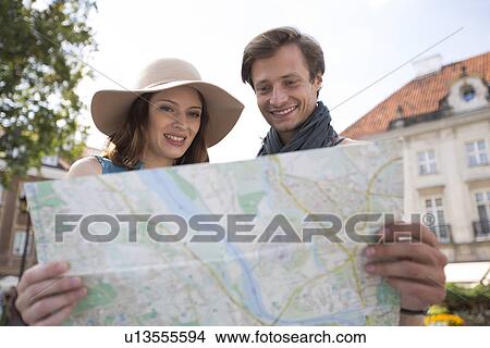 Happy tourist couple reading map outdoors View Large Photo Image Picture - Happy tourist couple reading map outdoors. Fotosearch
