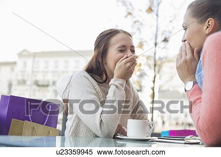 Stock Photography - Happy women sharing secrets at outdoor cafe. Fotosearch