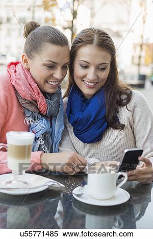 Happy women using cell phone at sidewalk cafe View Large Photo Image Stock Photography - Happy women using cell phone at sidewalk cafe. Fotosearch