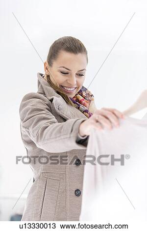 Happy young woman looking sweater in store View Large Photo Image Stock Image - Happy young woman looking sweater in store. Fotosearch