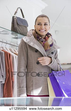 Happy young woman with shopping bags in store View Large Photo Image Picture - Happy young woman with shopping bags in store. Fotosearch