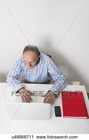 High angle view of senior businessman using laptop at office desk View Large Photo Image Stock Image - High angle view of senior businessman using laptop at office desk. Fotosearch