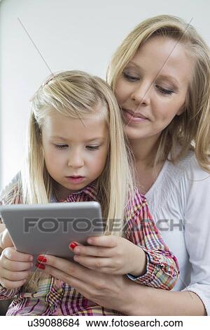 Loving woman with daughter using digital tablet at home View Large Photo Image Picture - Loving woman with daughter using digital tablet at home. Fotosearch