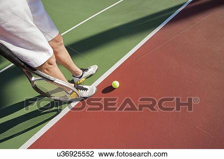 Stock Image - Low section of male tennis player on court. Fotosearch