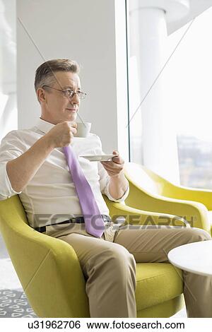 Mature businessman having coffee in lobby at office View Large Photo Image Stock Photograph - Mature businessman having coffee in lobby at office. Fotosearch