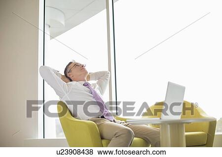 Stock Photo - Mature businessman relaxing in lobby. Fotosearch