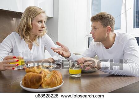 Mid adult couple talking while having breakfast at home View Large Photo Image Stock Photograph - Mid adult couple talking while having breakfast at home. Fotosearch