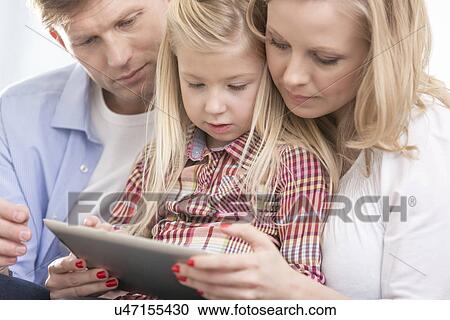 Mid adult parents using tablet PC with daughter at home View Large Photo Image Stock Image - Mid adult parents using tablet PC with daughter at home. Fotosearch