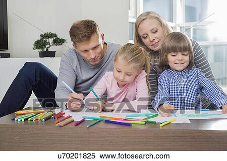 Stock Photography - Mid adult parents with children drawing together at home. Fotosearch