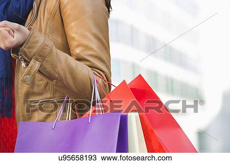 Mid section of woman carrying shopping bags View Large Photo Image Stock Image - Mid section of woman carrying shopping bags. Fotosearch