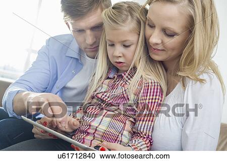Parents and daughter using tablet computer in living room View Large Photo Image Stock Image - Parents and daughter using tablet computer in living room. Fotosearch