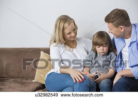 Parents sitting with upset son on sofa at home View Large Photo Image Stock Photo - Parents sitting with upset son on sofa at home. Fotosearch