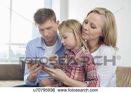 Parents with daughter using digital tablet at home View Large Photo Image Stock Photograph - Parents with daughter using digital tablet at home. Fotosearch