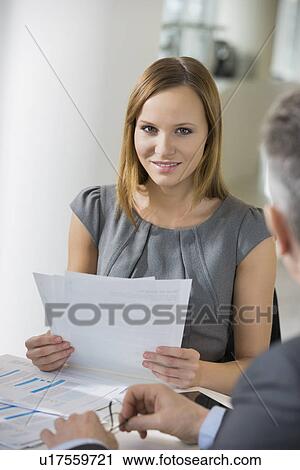 Stock Image - Portrait of beautiful businesswoman with documents in office cafeteria. Fotosearch