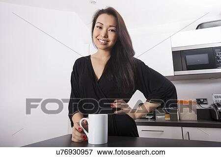 Portrait of beautiful young woman having coffee in kitchen View Large Photo Image Stock Photo - Portrait of beautiful young woman having coffee in kitchen. Fotosearch