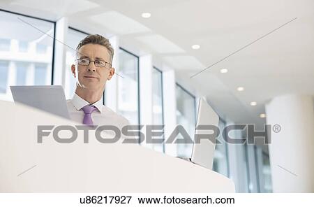 Portrait of businessman with laptop and documents at railing View Large Photo Image Stock Photo - Portrait of businessman with laptop and documents at railing. Fotosearch