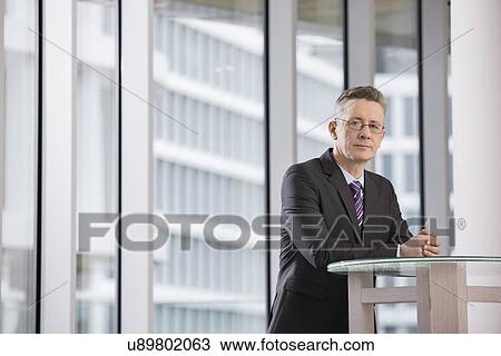 Portrait of confident businessman standing in office View Large Photo Image Stock Image - Portrait of confident businessman standing in office. Fotosearch