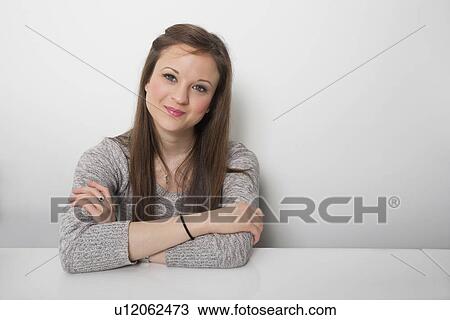 Stock Image - Portrait of confident businesswoman sitting at desk in office. Fotosearch