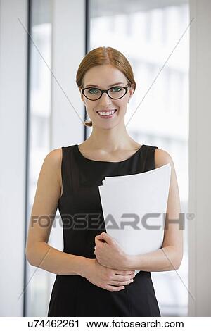 Portrait of confident businesswoman holding documents in office View Large Photo Image Stock Image - Portrait of confident businesswoman holding documents in office. Fotosearch