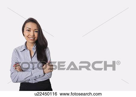 Portrait of confident businesswoman standing arms crossed against gray background View Large Photo Image Stock Photograph - Portrait of confident businesswoman standing arms crossed against gray background. Fotosearch