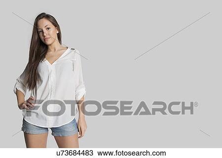 Portrait of confident girl in hot pants posing against gray background View Large Photo Image Stock Image - Portrait of confident girl in hot pants posing against gray background. Fotosearch