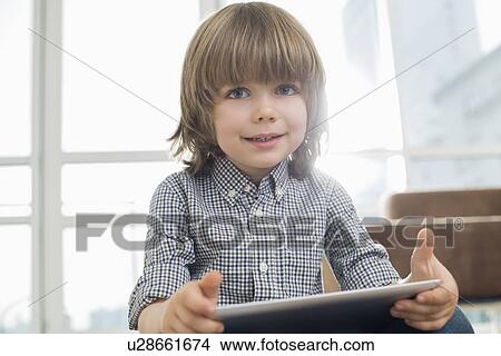 Portrait of cute boy holding tablet computer at home View Large Photo Image Picture - Portrait of cute boy holding tablet computer at home. Fotosearch