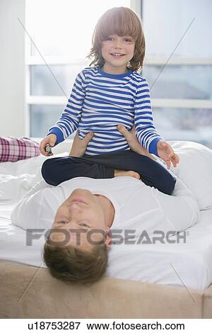 Portrait of cute boy playing with father in bedroom View Large Photo Image Stock Photo - Portrait of cute boy playing with father in bedroom. Fotosearch