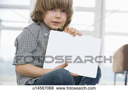 Stock Photo - Portrait of cute boy showing his drawing on digital tablet at home. Fotosearch