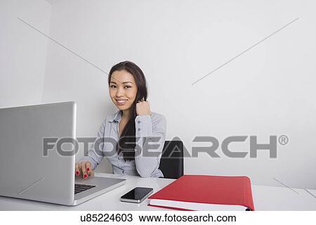 Portrait of happy businesswoman using laptop at office desk View Large Photo Image Stock Image - Portrait of happy businesswoman using laptop at office desk. Fotosearch