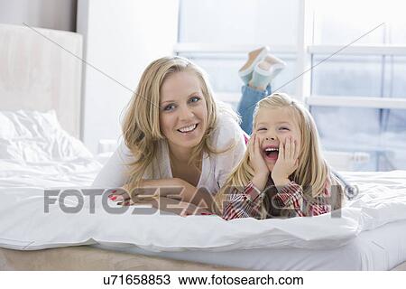 Portrait of happy mother and daughter lying in bed View Large Photo Image Stock Image - Portrait of happy mother and daughter lying in bed. Fotosearch
