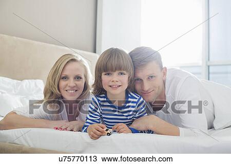 Portrait of happy parents lying with son in bed View Large Photo Image Stock Image - Portrait of happy parents lying with son in bed. Fotosearch
