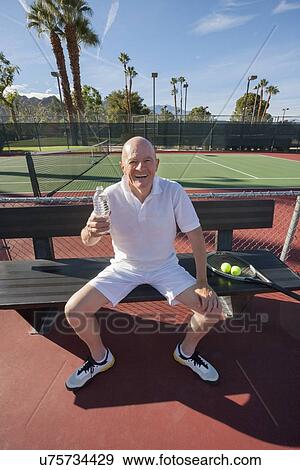Portrait of happy senior male tennis player with water bottle relaxing on court View Large Photo Image Stock Photo - Portrait of happy senior male tennis player with water bottle relaxing on court. Fotosearch