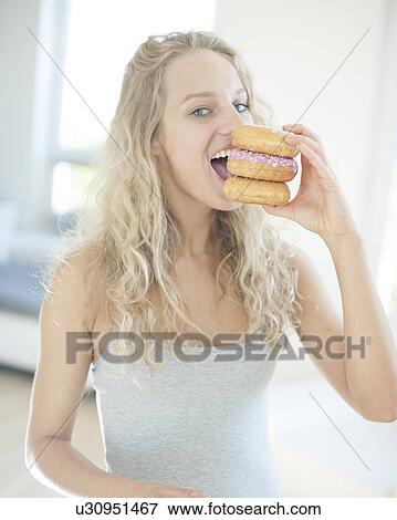 Portrait of happy woman eating donuts in house View Large Photo Image Stock Photo - Portrait of happy woman eating donuts in house. Fotosearch