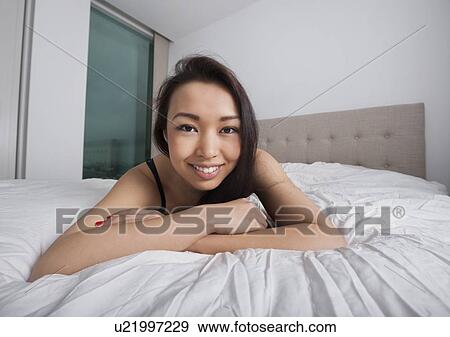 Stock Photo - Portrait of happy young woman resting in bed. Fotosearch