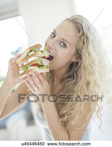 Portrait of impatient woman eating large sandwich in house View Large Photo Image Stock Image - Portrait of impatient woman eating large sandwich in house. Fotosearch