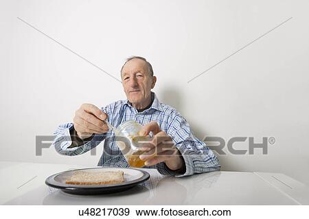 Portrait of senior man preparing slice of bread and marmalade at table View Large Photo Image Stock Photo - Portrait of senior man preparing slice of bread and marmalade at table. Fotosearch