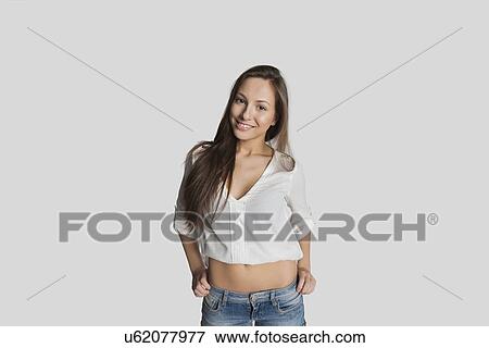Stock Photo - Portrait of smiling teenage girl in crop top posing against gray background. Fotosearch