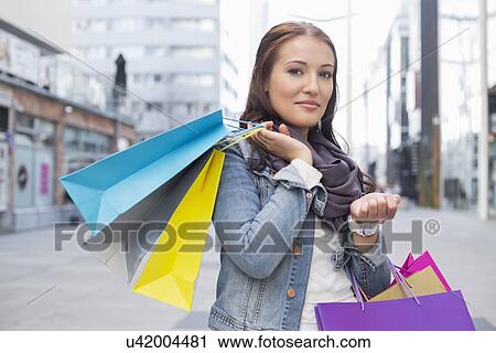 Stock Image - Portrait of woman carrying shopping bags. Fotosearch