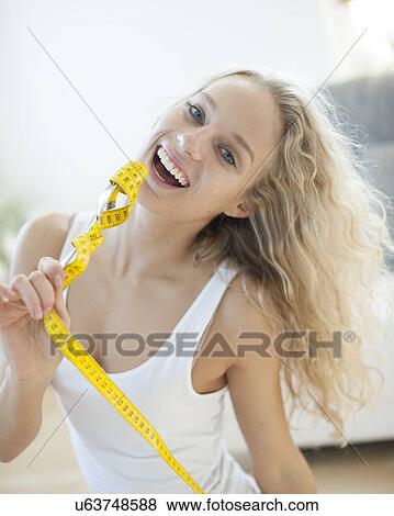 Portrait of woman laughing while holding fork wrapped with measuring tape View Large Photo Image Stock Photo - Portrait of woman laughing while holding fork wrapped with measuring tape. Fotosearch