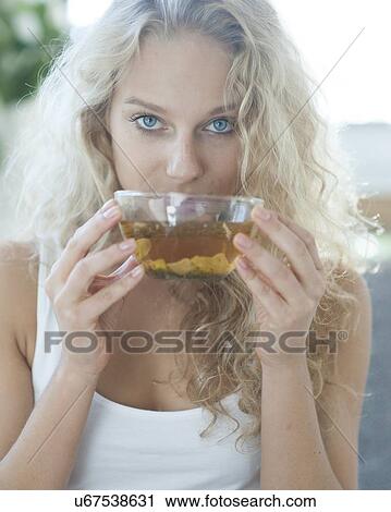 Stock Image - Portrait of young woman drinking herbal tea. Fotosearch