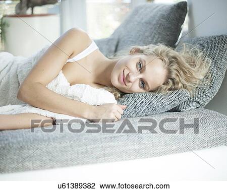 Portrait of young woman lying on sofa at home View Large Photo Image Stock Image - Portrait of young woman lying on sofa at home. Fotosearch