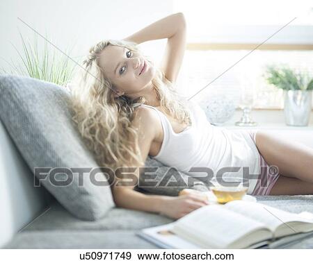 Portrait of young woman with herbal tea relaxing on sofa View Large Photo Image Stock Photo - Portrait of young woman with herbal tea relaxing on sofa. Fotosearch