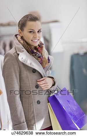Portrait of young woman with shopping bags in store View Large Photo Image Stock Photo - Portrait of young woman with shopping bags in store. Fotosearch